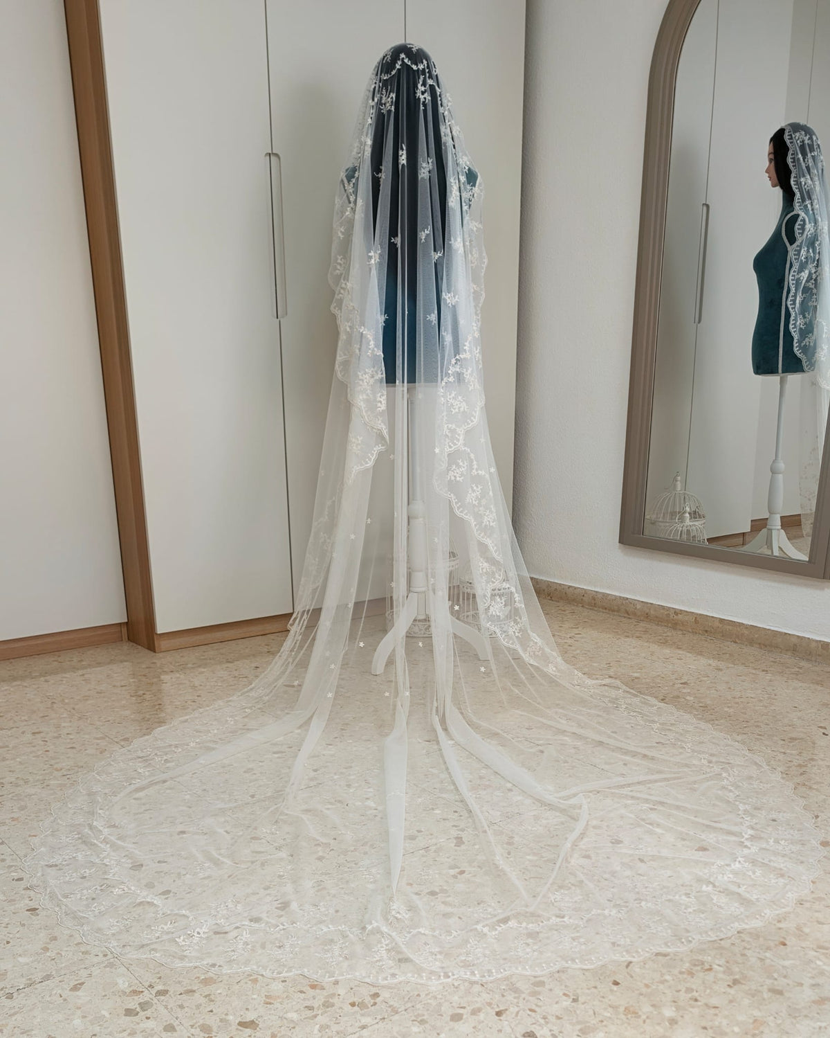 Vista trasera de una mantilla de novia ovalada larga con bordado floral continuo de Zulema Torres extendida en el suelo.