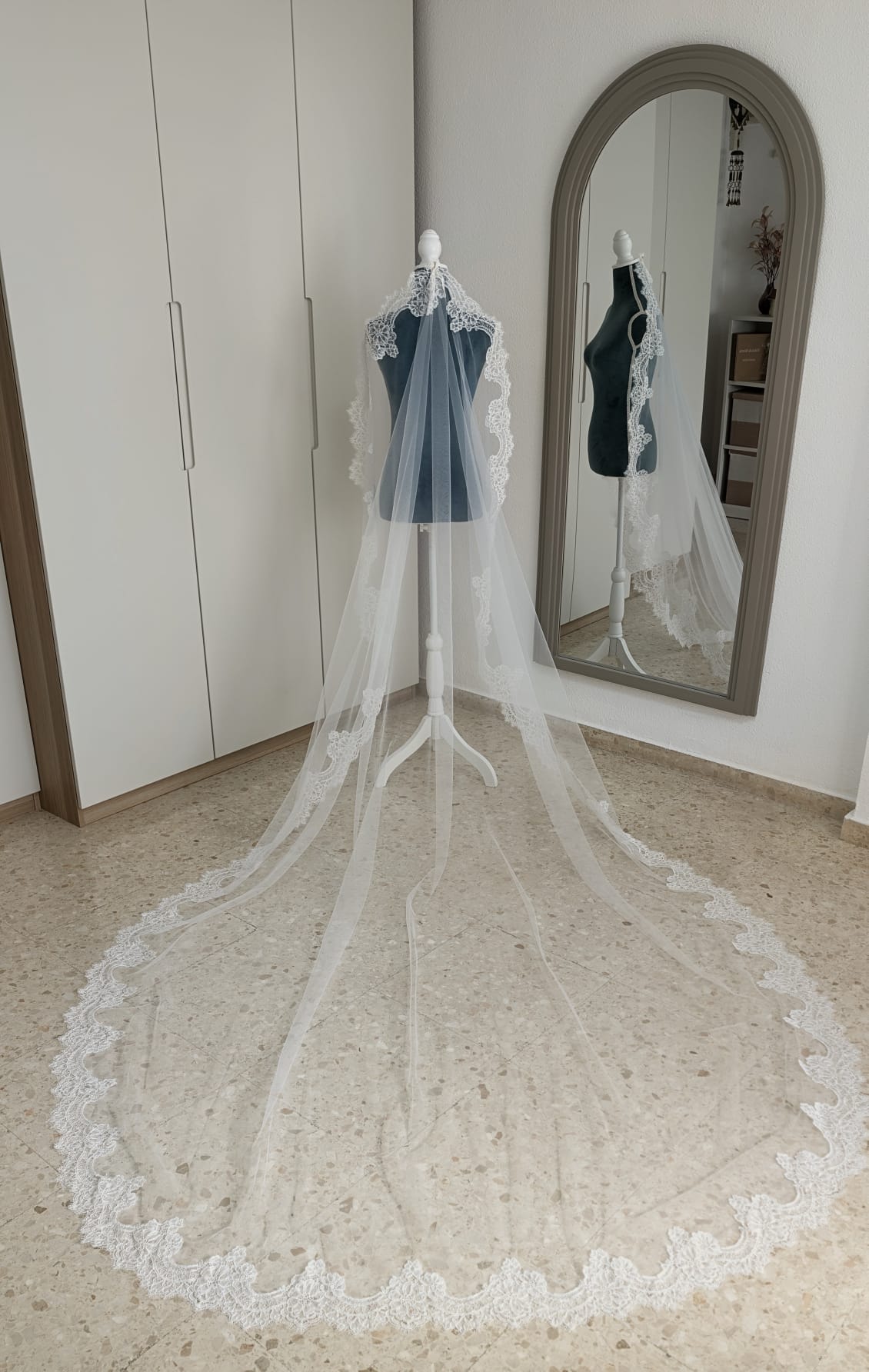 Vista aérea de la cola extendida en abanico de un velo de novia largo de tul soft blanco natural con encaje rebrodé perimetral, modelo 5194 de Zulema Torres.