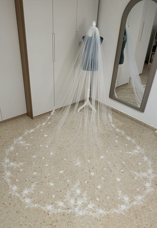 Vista aérea de un velo de novia largo de 3x3,50 metros confeccionado en tul diamante con espectaculares aplicaciones de encaje y flores 3D en la cola.
