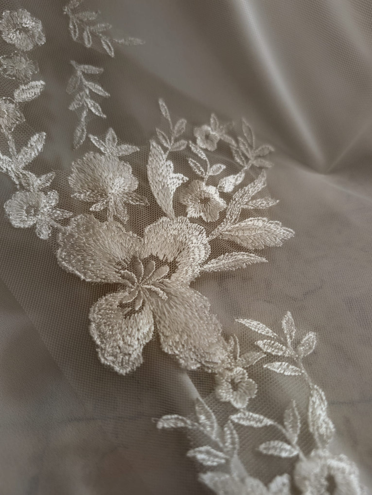 Detalle de los apliques de encaje floral y pedrería en un velo de novia de tul de Zulema Torres.