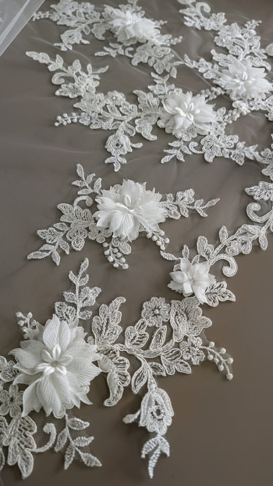 Primer plano de flores tridimensionales de tela y bordados de hojas en relieve sobre el contorno de un velo de novia de Zulema Torres.