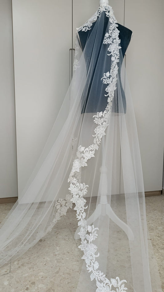 Velo de novia largo modelo 9442 de Zulema Torres expuesto en maniquí, confeccionado en tul soft blanco natural con encaje rebrodé floral perimetral.