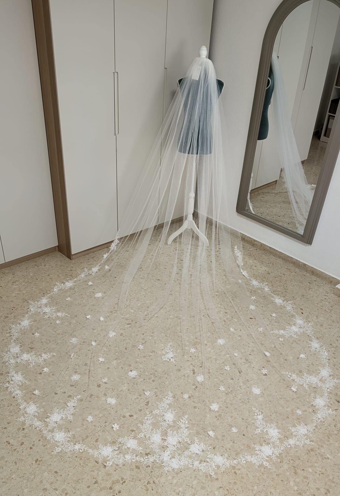 Vista aérea de un velo de novia largo de 3x3,50 metros confeccionado en tul diamante con espectaculares aplicaciones de encaje y flores 3D en la cola.