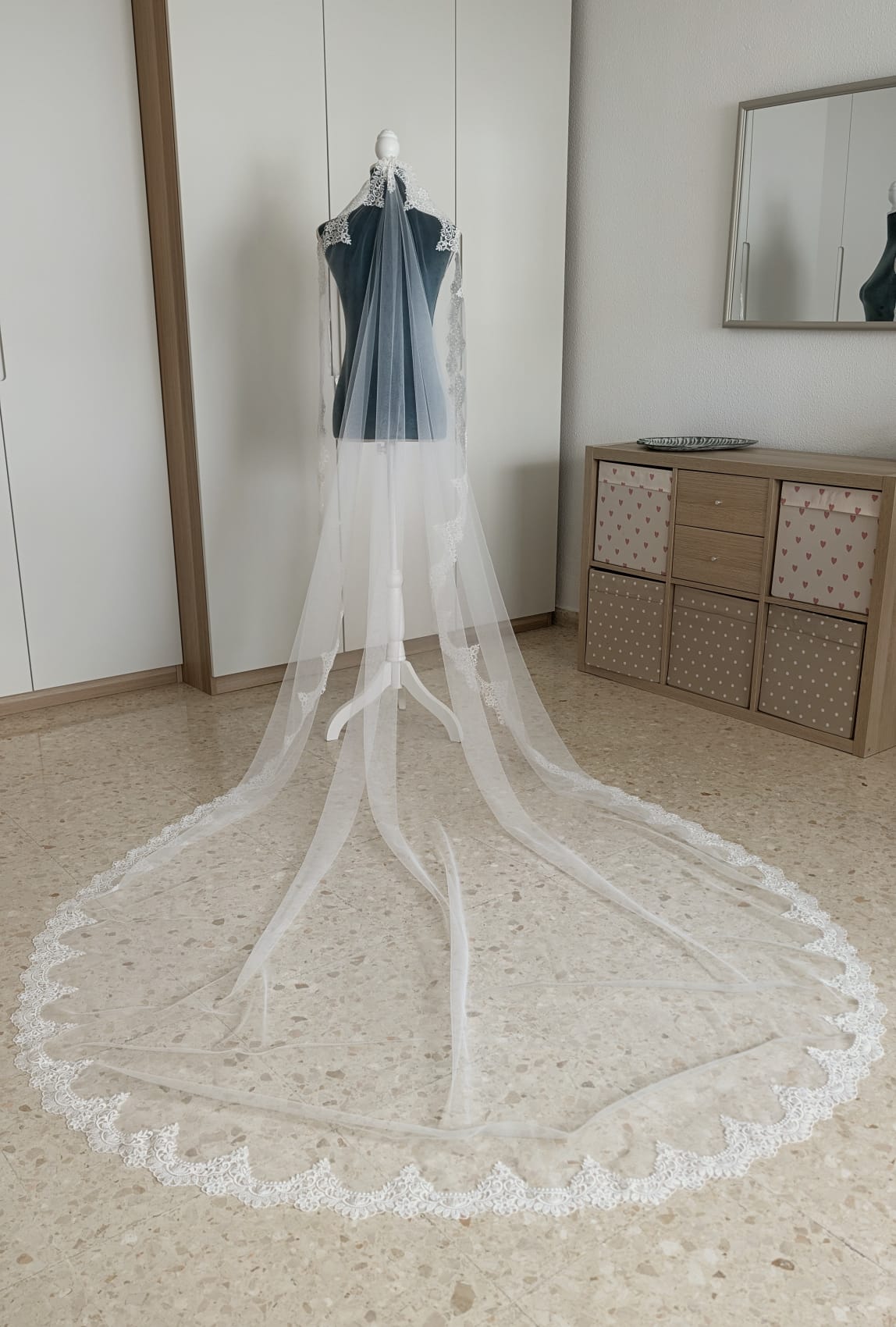 Vista aérea de un velo de novia largo estilo capilla de 2x3 metros con la cola extendida en abanico y encaje perimetral.