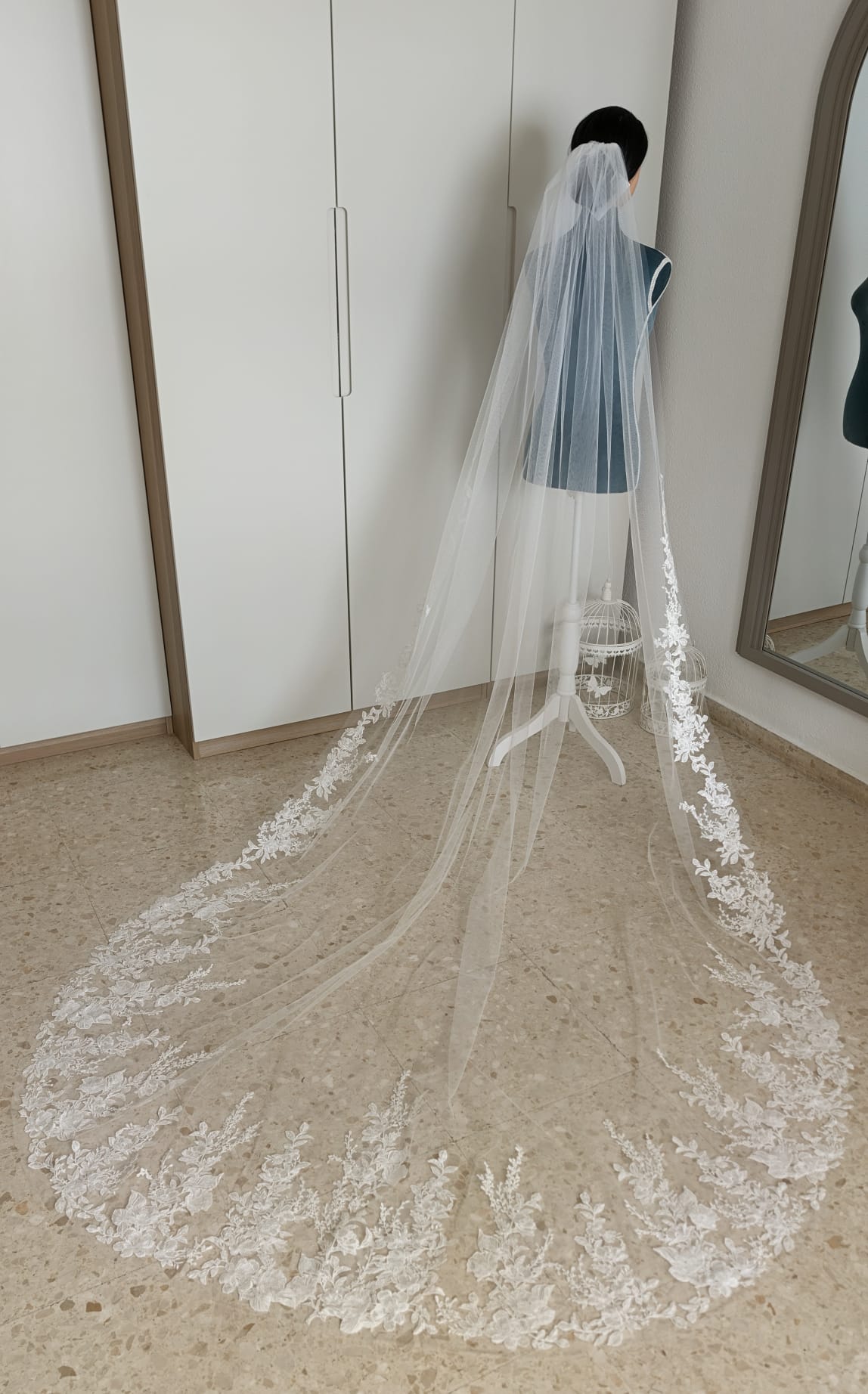 Vista completa de un velo de novia de 2x3 metros en tul diamante con la cola extendida y encaje floral que sube hasta la cintura.
