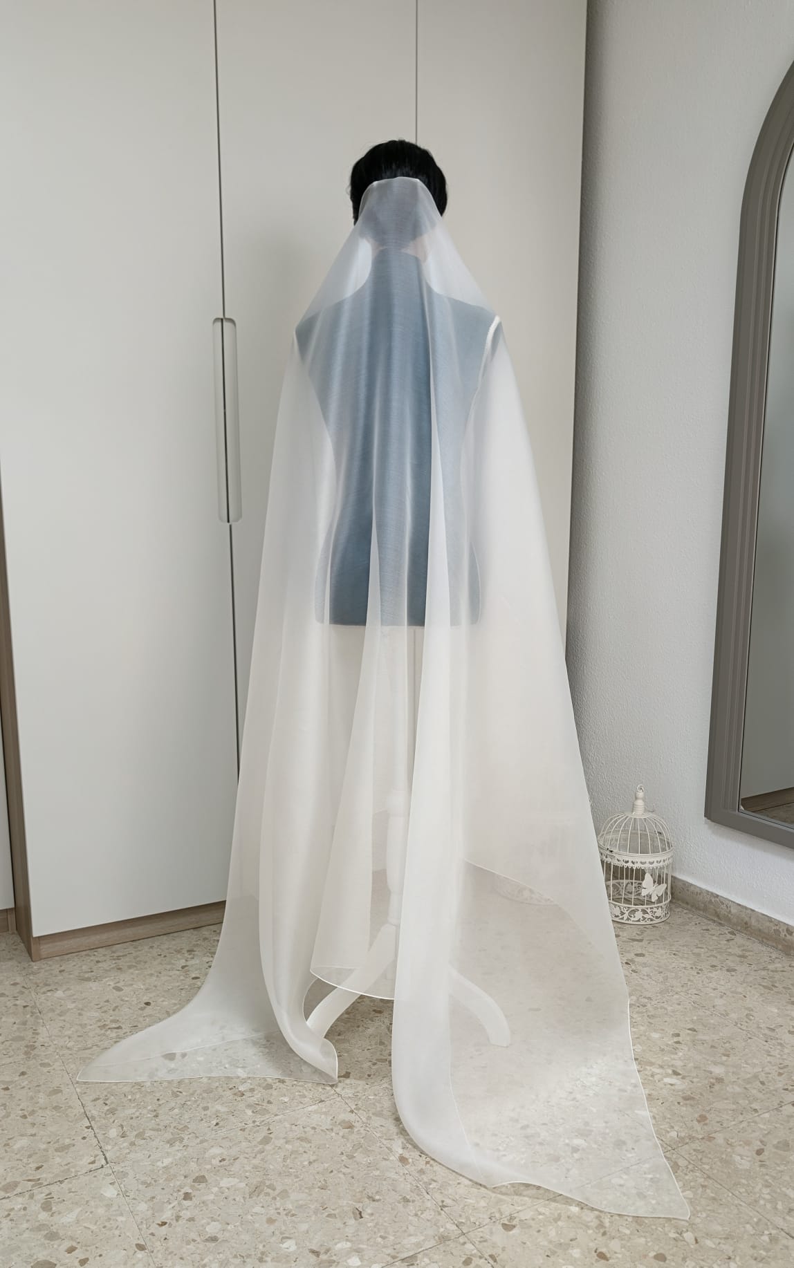 Vista trasera de un velo de novia minimalista confeccionado en organza 100% de seda blanco natural sobre un maniquí.