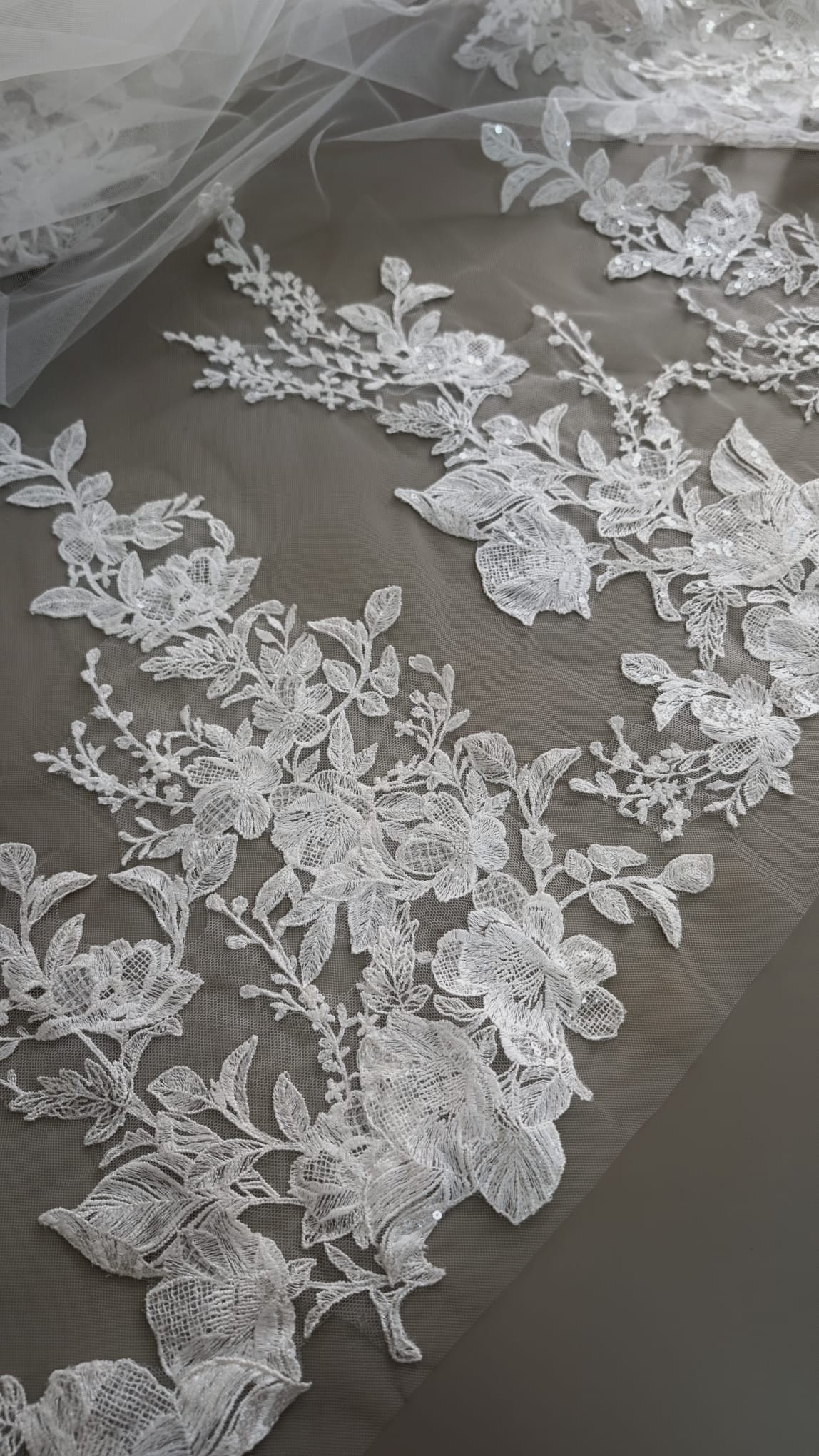 Primer plano de apliques de encaje floral bordado con detalles de lentejuelas brillantes sobre tul transparente de Zulema Torres.