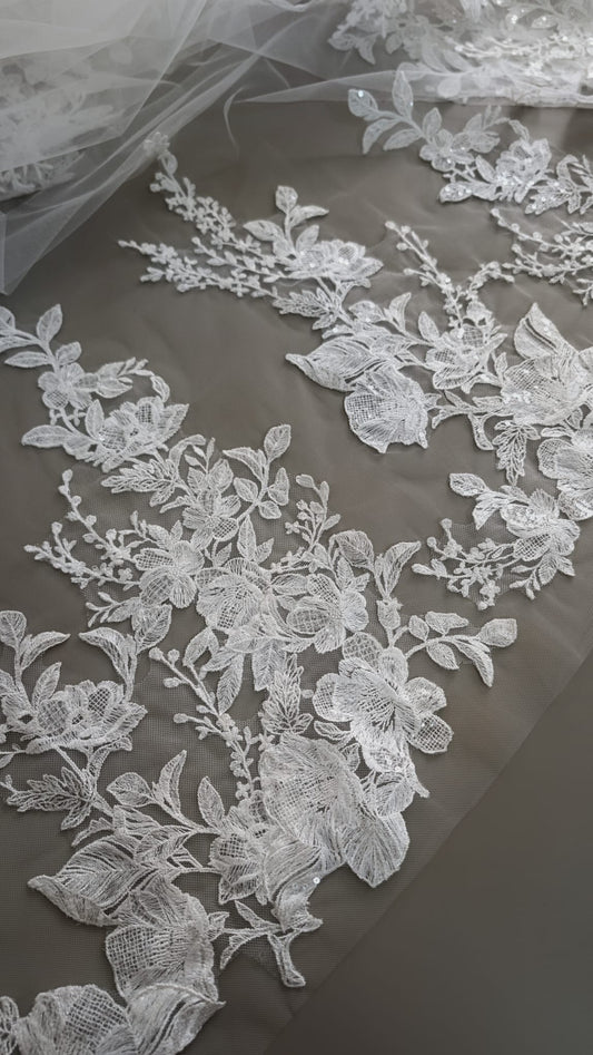 Primer plano de apliques de encaje floral bordado con detalles de lentejuelas brillantes sobre tul transparente de Zulema Torres.